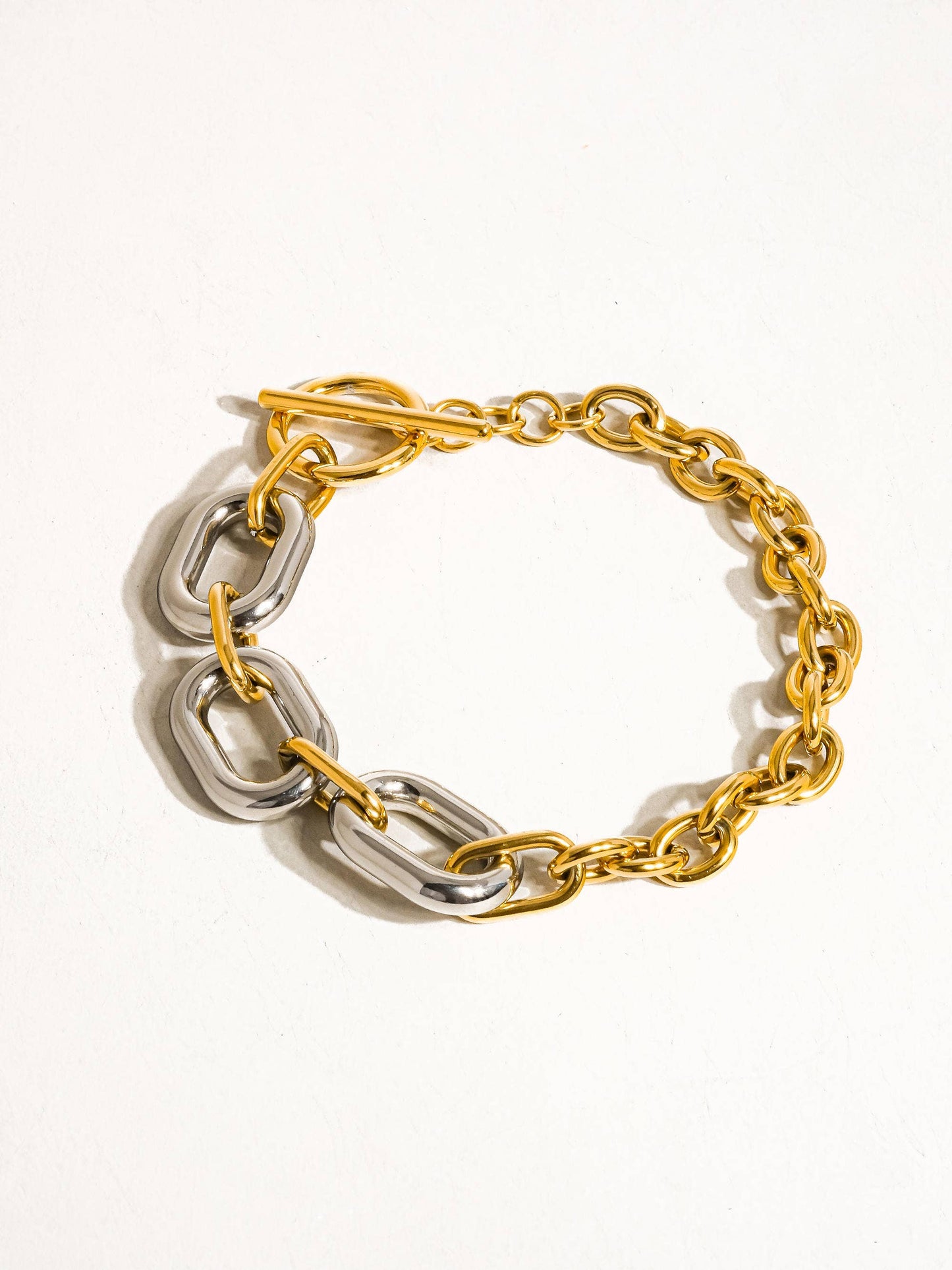 a gold and silver chain bracelet on a white background