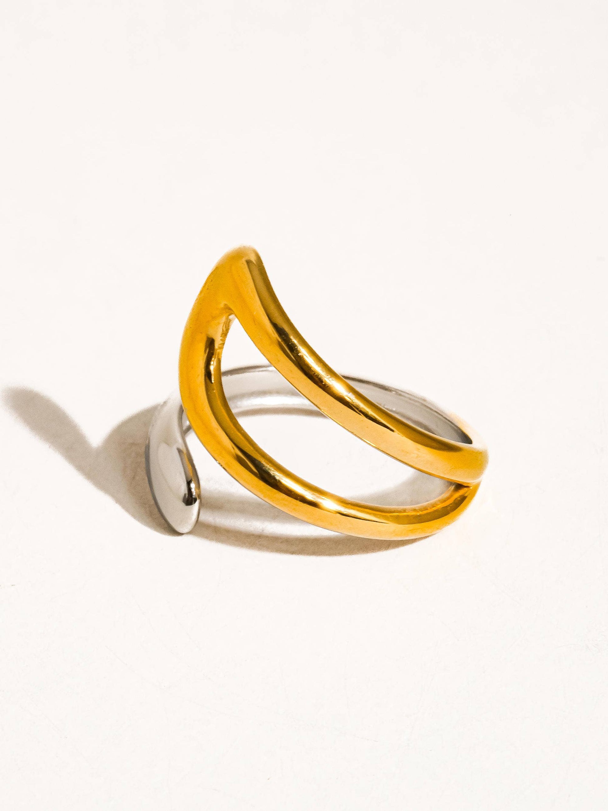 a gold ring with two curved sections on a white background