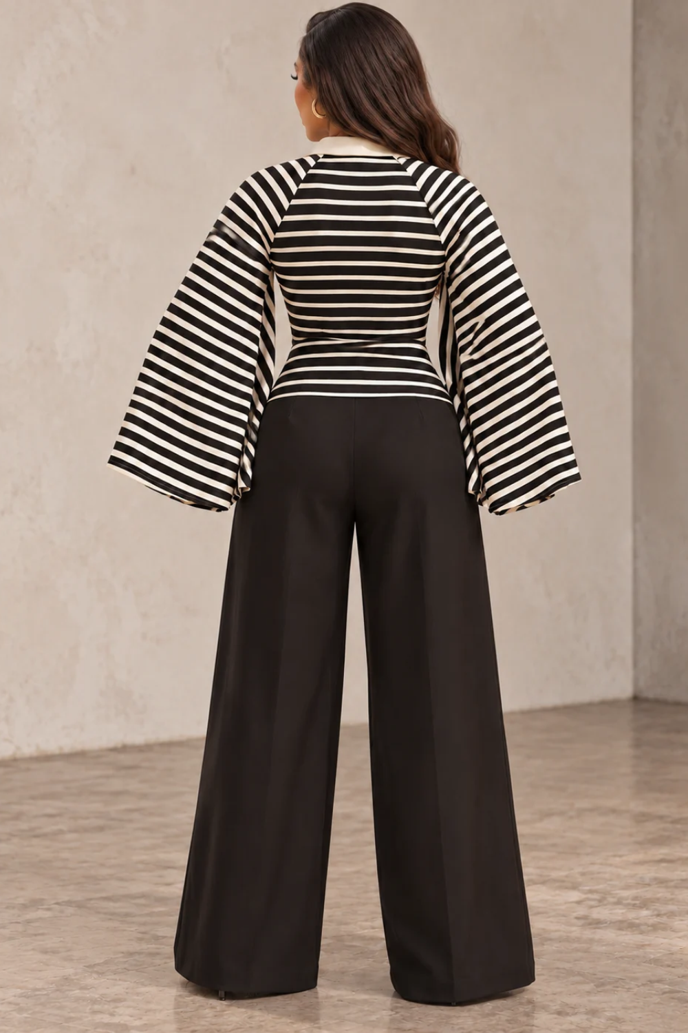 Model wearing the Bellamy black and ivory striped kimono-sleeve collared top with dramatic wide sleeves and a contrast polo collar, styled with black wide-leg trousers at Blaire Shop